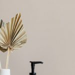 Beauty Essentials - Set of cosmetic supplies near decorative leaves in vase on marble shelf